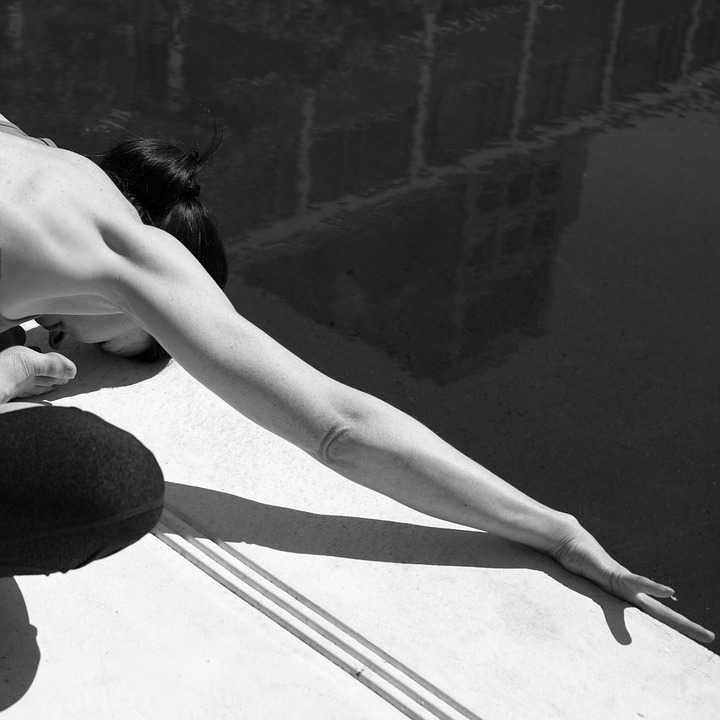 women folding forward in a seated yoga posture.